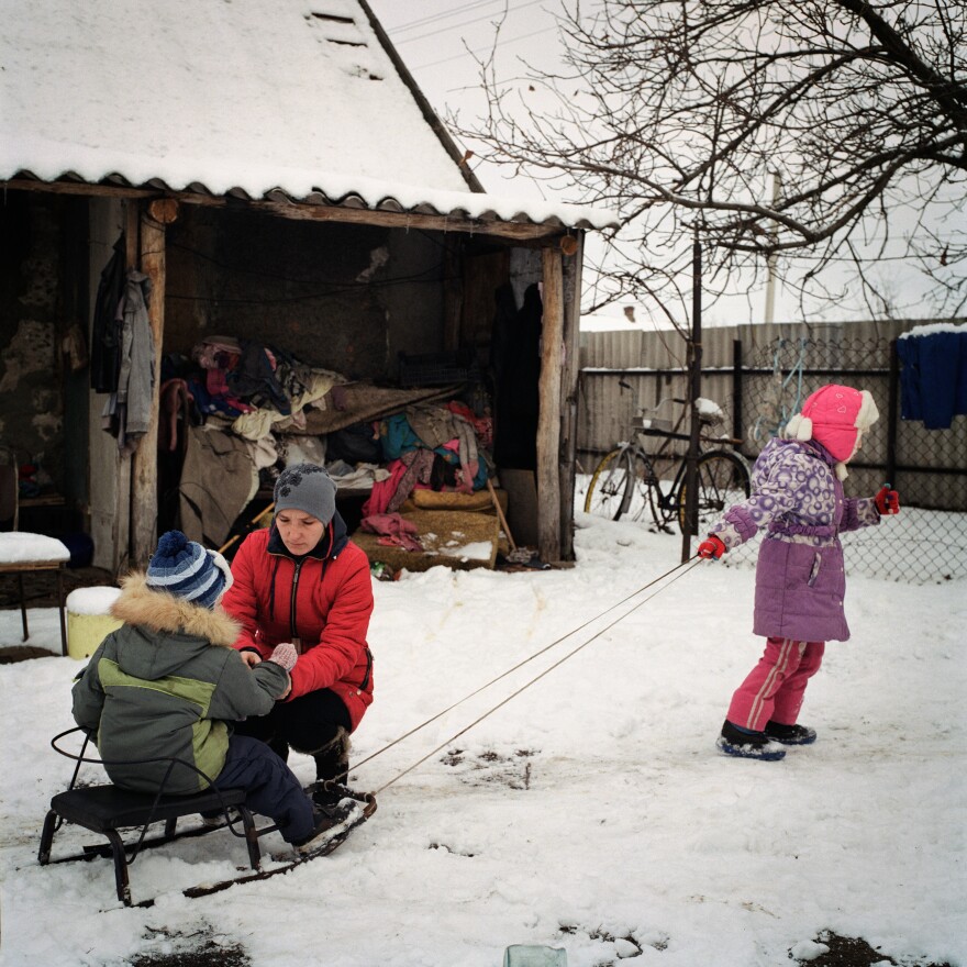 Miroslava pulls Kirill on a sled while Olga puts on his mittens in January 2021. The Griniks got used to a "new normal" after one year of COVID-19 and seven years of war. Shelling could still be heard on the outskirts of town. Other consequences of the conflict also took their toll: disrupted infrastructure, lack of access to medical services and limited employment opportunities.