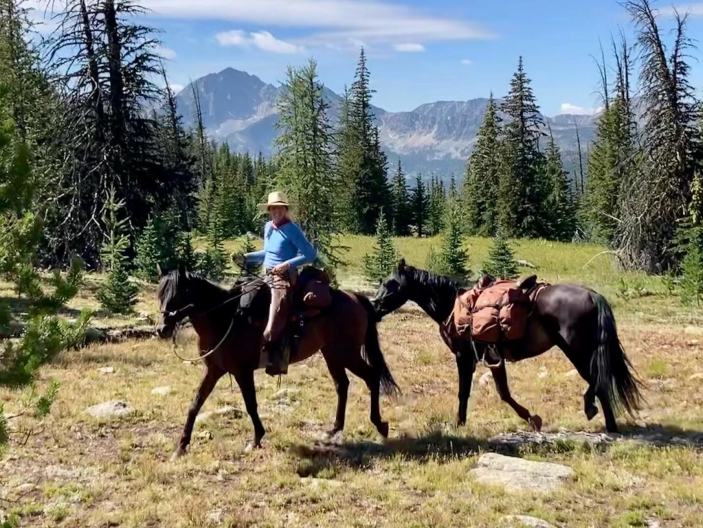 Host Ashley Ahearn riding her mare, Pistol, and leading her three-year-old mustang, Boo, in the mountains of Washington.