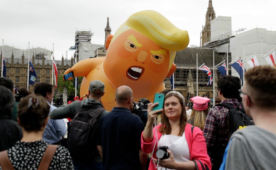 A woman takes a selfie as the "Trump Baby" blimp is inflated in Parliament Square in Central London at the start of the demonstrations.