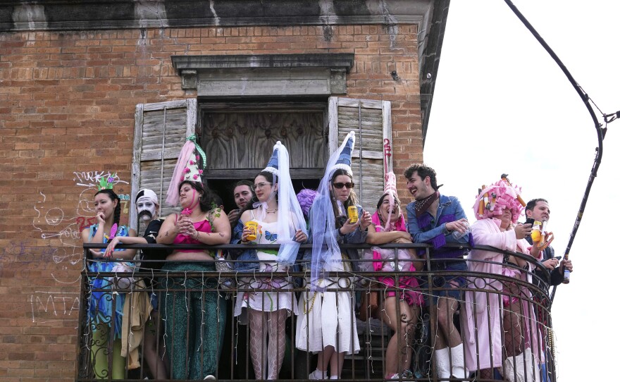 People watch from a balcony during the Society of Saint Anne's parade on Mardi Gras Day, Tuesday, March 4, 2025 in New Orleans. (AP Photo/Gerald Herbert)