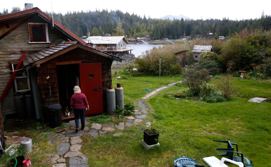 Cassy and the family cat walk across the Peaveys' property in Meyers Chuck, a view of the water in the distance.