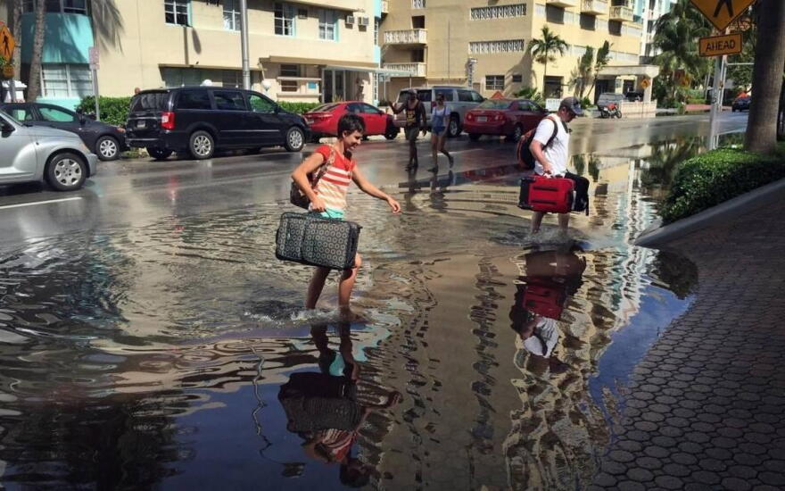 Oakley and Casey Jones, tourists from Idaho Falls, navigate the flooded streets of Miami Beach as they try to make their way to their hotel on Collins Avenue and 30th Street during a King Tide on Monday, Sept. 28, 2015.