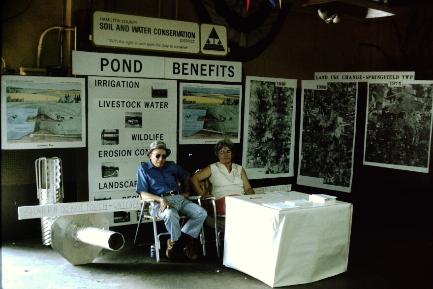 A man and a woman sit at a booth for the Hamilton County Conservation District.