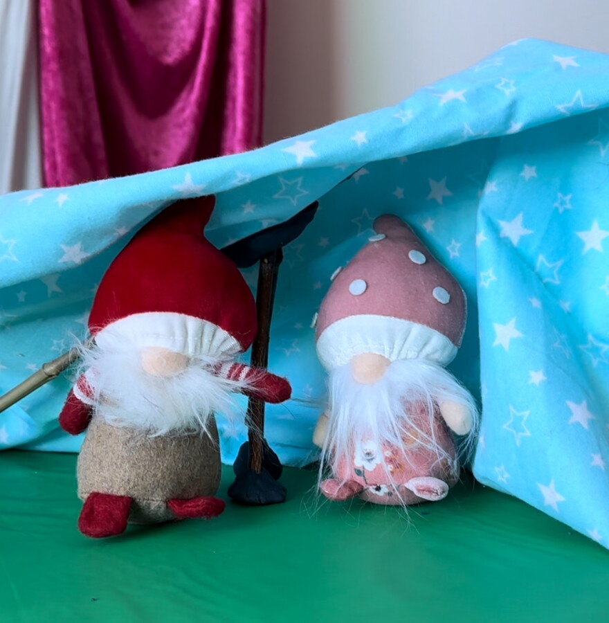 Two gnomes demonstrate a miniature blanket fort using sticks and Play-Doh for supports at the Strong National Museum of Play.
