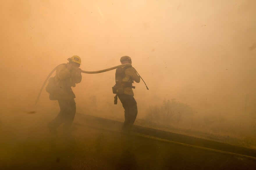 Firefighters battle a fire along the Ronald Reagan Freeway in Simi Valley, Calif.