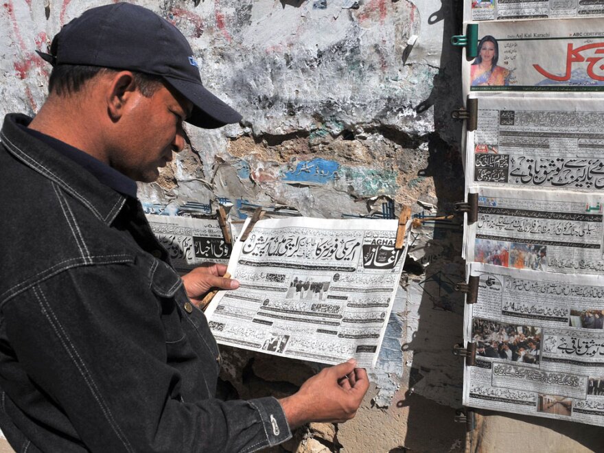 A man at a newsstand in Karachi, Pakistan, reads an Urdu-language evening newspaper reporting the capture of a top Taliban commander.