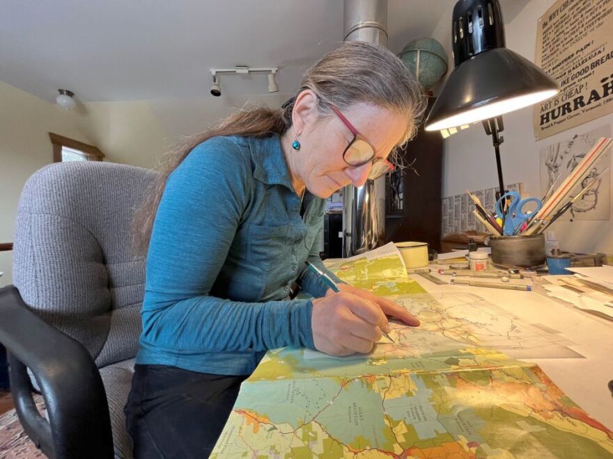 Artist Nancy Bernstein traces over a detail on a map from the Adirondack Park Agency to add to her map for Historic Saranac Lake.