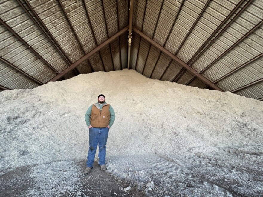 Michael Cutchins stands in front of a mountain of cottonseeds that have been removed by a cotton gin. Selling these seeds brings in a majority of the Northwest Cotton Growers Co-op's revenue.