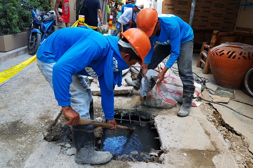 Municipal workers try to clear sewage from one of the alleys leading to White Beach before it overflows. The scene is repeated all over the island as residents try to cope with overbuilding and often illegal connections to the sewage system.
