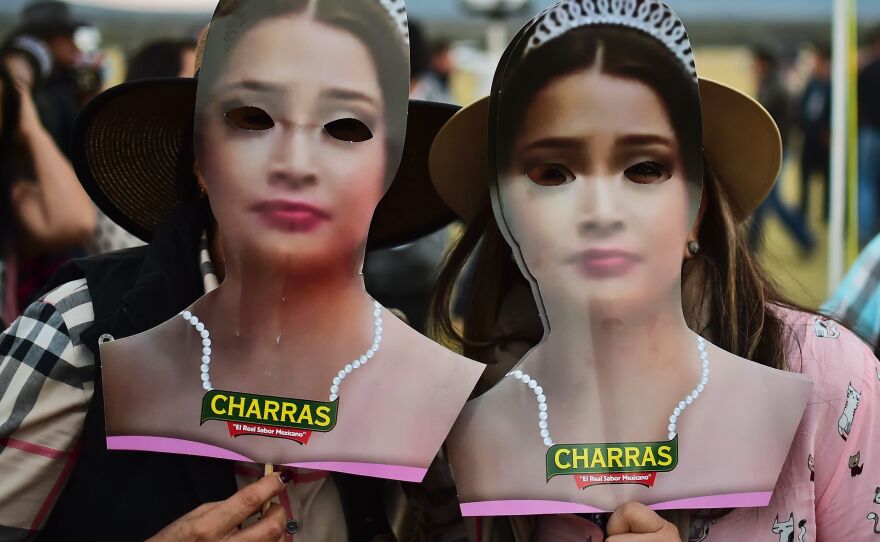Two women hold masks depicting Mexican teenager Rubi Ibarra during her 15th birthday party on Monday.