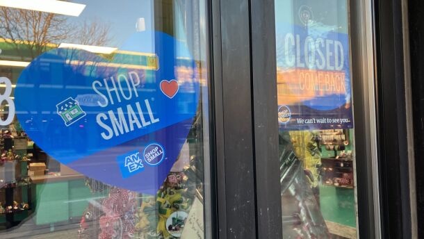 A blue sign on a shop window asks people to "shop small."