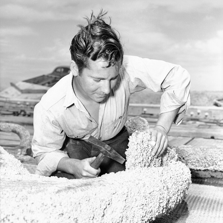 Leo L. Edwards' 18, scrapes barnacles from an anchor in 1946.