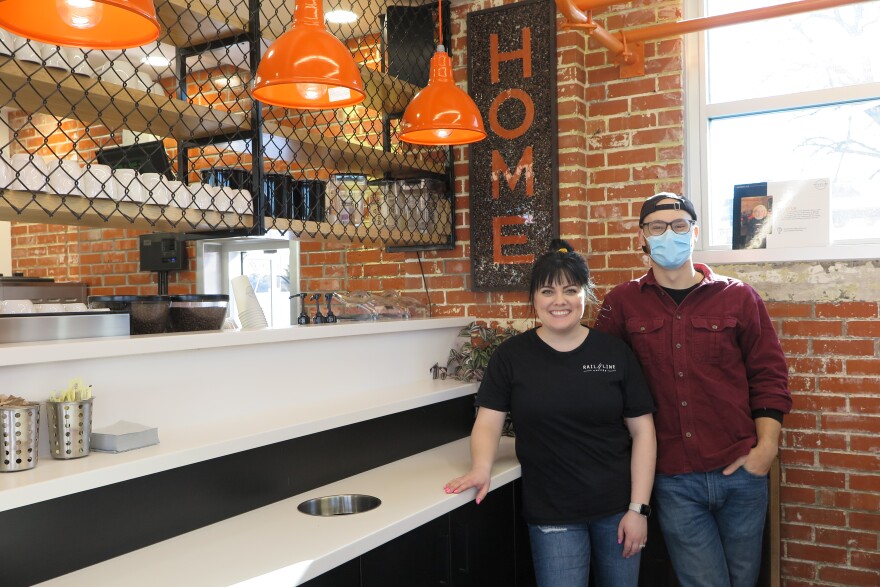 Assistant Manager Kaitlyn McKinley and Supervisor Colin Sauskojus of Rail Line Coffee in a stand in front of the espresso counter in the remodeled gas station and auto repair shop. Here, coffee is served with a purpose to revitalize and enliven the south side.