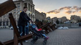 A family walks through a barricade at a nearly deserted Maidan Square on in Kyiv, Ukraine.
