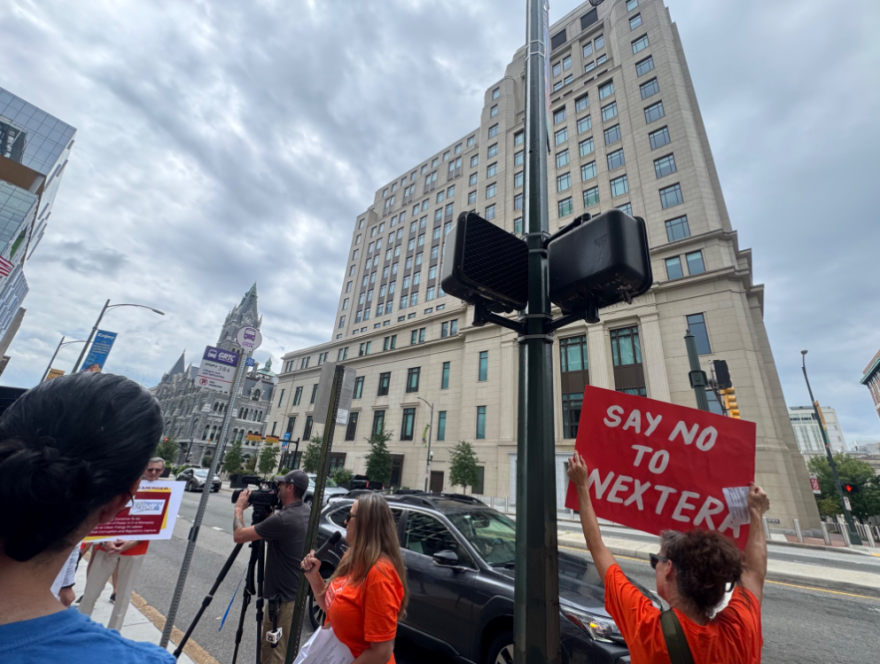 Protestors gather outside the Virginia General Assembly building ahead of a meeting of the Virginia Energy Commission to oppose the merger between Virginia's Dominion Energy and Florida's NextEra.
