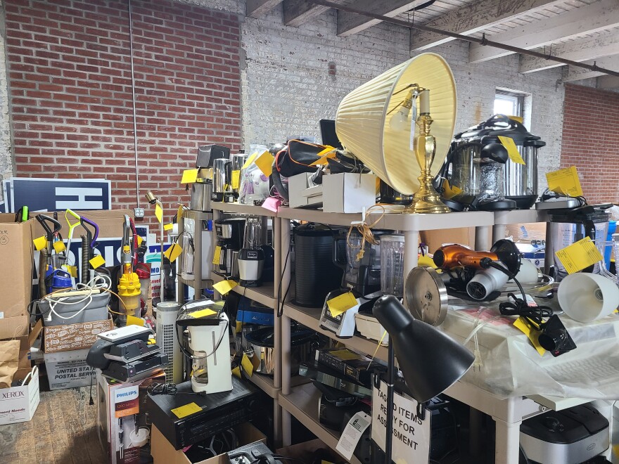 shelves of broken appliances overflow on the floor of a warehouse