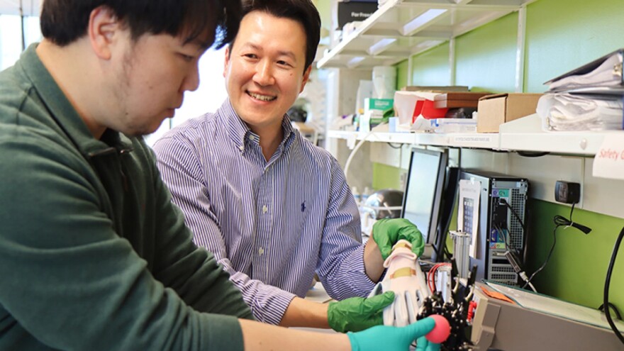 Using a robotic hand, Jinwook Baek (left), postdoctoral research assistant, and Sunghwan Lee, assistant professor of engineering technology, examine how a flexible and wearable sensor could be used to monitor health information and manipulate a small object (ball).