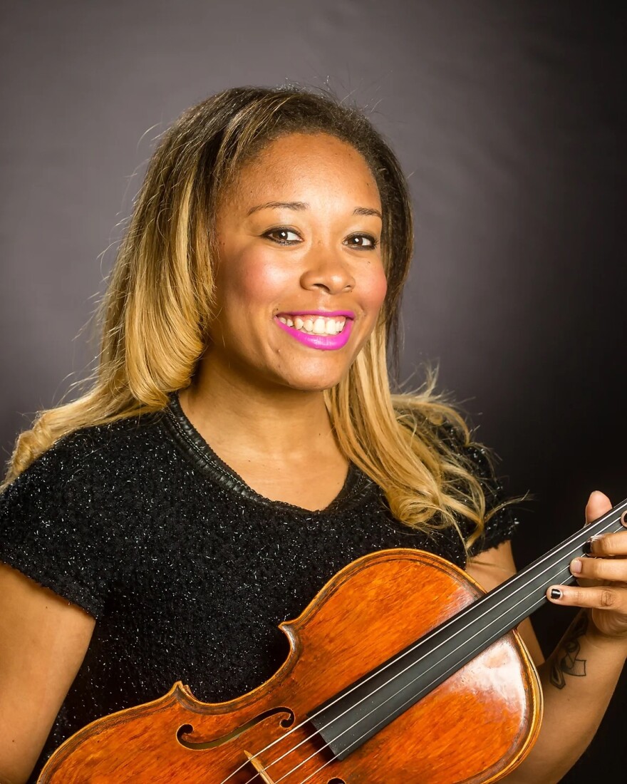 African woman with long hair holding her violin