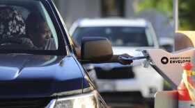 A driver slides multiple ballots into a collection box at a voting drop box location, Tuesday, Nov. 8, 2022, in Honolulu. (AP Photo/Marco Garcia)