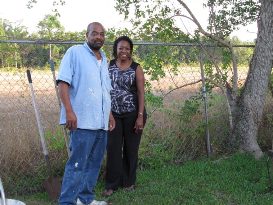 Anthony and Eunice Crane stand in their backyard in Gulfport, Miss. The new port access road will be built behind their fence. Their home used to back to other homes.