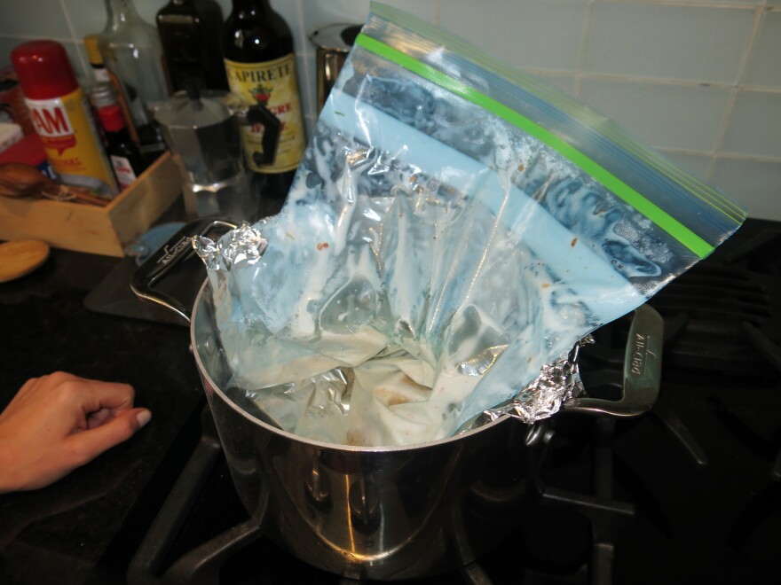 Set a piece of tin foil in the pot like a hammock (with the ends folded over the edge). Then put the bag into the pot of hot — but not boiling — water.
