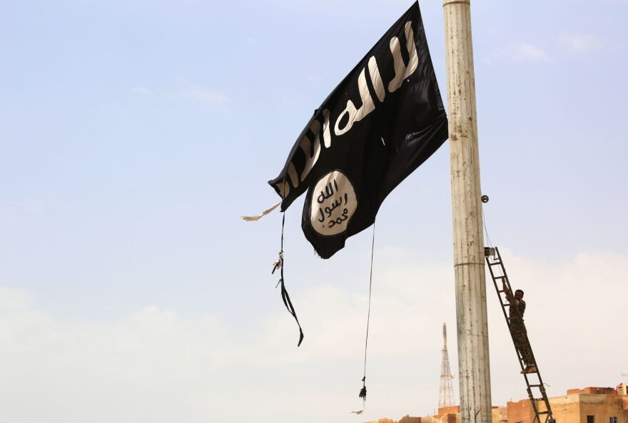 A member of the U.S.-backed Syrian Democratic Forces removes an Islamic State group flag in the town of Tabqa, about 55 kilometres (35 miles) west of Raqqa, on April 30, 2017. (Delil Souleiman/AFP/Getty Images)