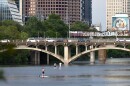 People paddle board on Lady Bird Lake near the Lamar bridge.
