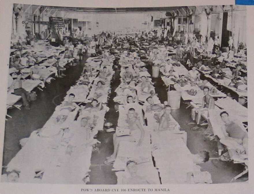 a large group of POWs laying on cots