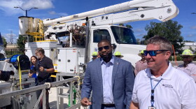 Two men standing outside next to a bucket truck