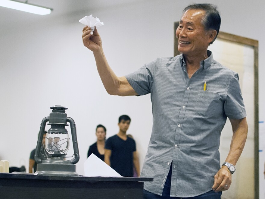 Takei rehearses a scene in which his character, Ojii-San, tries to cheer his granddaughter up by making her an origami flower out of a loyalty questionnaire.