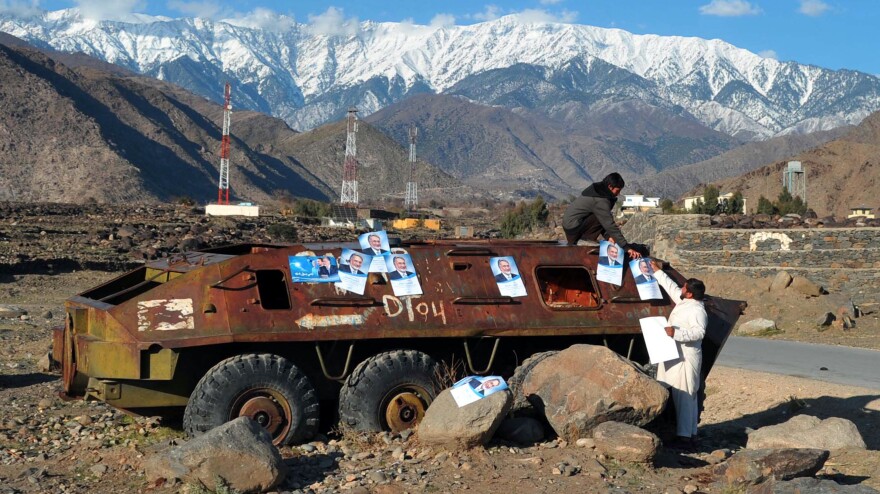 Afghan workers paste election campaign posters for presidential candidate Zalmai Rassoul on the rusted remains of a Soviet-era military vehicle near the eastern city of Jalalabad on Monday.