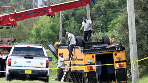 A vehicle recovery crew work to right an overturned school bus after a fatal collision, Monday, Oct. 5, 2026, in Winter Haven, Fla.