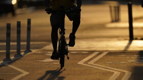 FILE - The sun sets behind a cyclist in a bike lane on Pennsylvania Avenue in Washington
