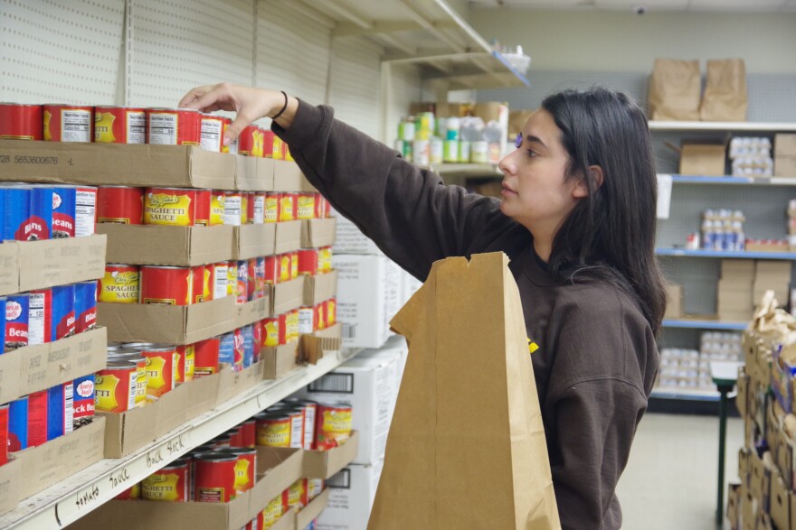 Western Michigan University student volunteer Alexis Ehlebracht packs a bag with items at Kalamazoo Loaves and Fishes