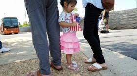 A girl holding a U.S. flag waits with her parents for Afghan relatives at a processing center for refugees evacuated from Afghanistan at the Dulles Expo Center near Dulles International Airport in Chantilly, Virginia, U.S., August 24, 2021.