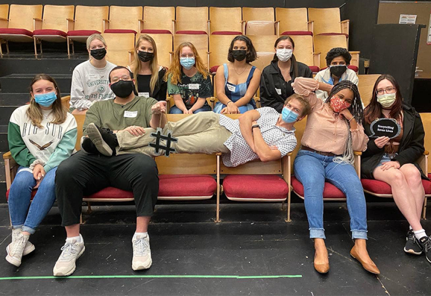 Cast members of the show pose for a picture -seated in the theater.