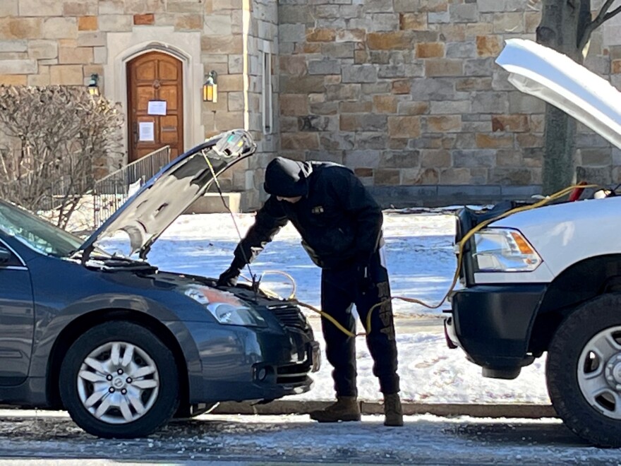 A motorist jumps his car on a cold winter's day.