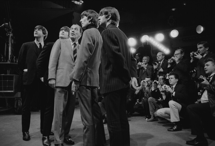 black and white photograph of The Beatles with Ed Sullivan and photographers behind them on , February 8, 1964. New York City.