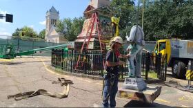 Photo from BLM757's Facebook. A worker guides a beheaded stone Confederate monument off its perch while removing the structure Wednesday morning.