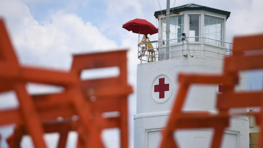 From the historic lifeguard station on the oceanfront, a lifeguard keeps an eye on beachgoers in May 2020.