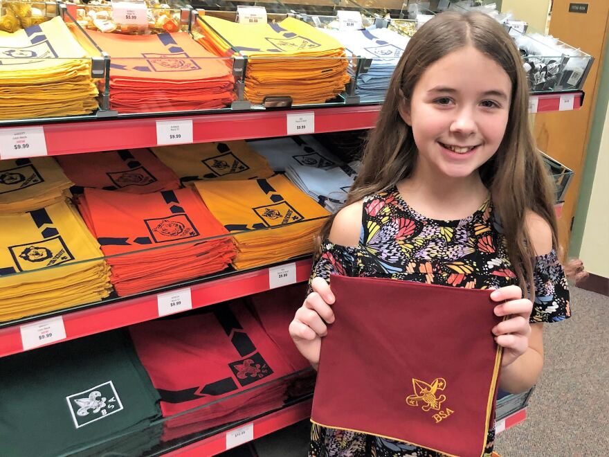 Elly Riegner, 12, holds up a red and gold neckerchief with the Scouts BSA logo. Riegner and her mother, Abby, were looking through the various colors and designs for uniforms in preparation for their new all-girls troop.