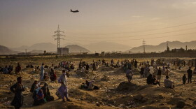 A military transport plane launches off while Afghans who cannot get into the airport to evacuate, watch and wonder while stranded outside, in Kabul, Afghanistan. (Marcus Yam / Los Angeles Times via Getty Images)