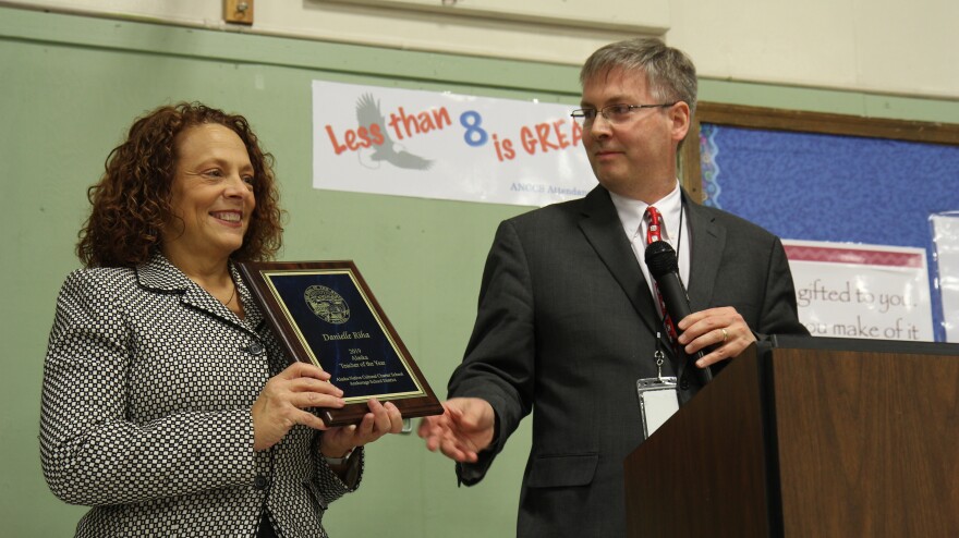 State Education department official Bob Williams presents Danielle Riha with the plaque commemorating her selection as the 2019 Alaska Teacher of the Year. (Photo by Kirsten Swann, Alaska Public Media - Anchorage)