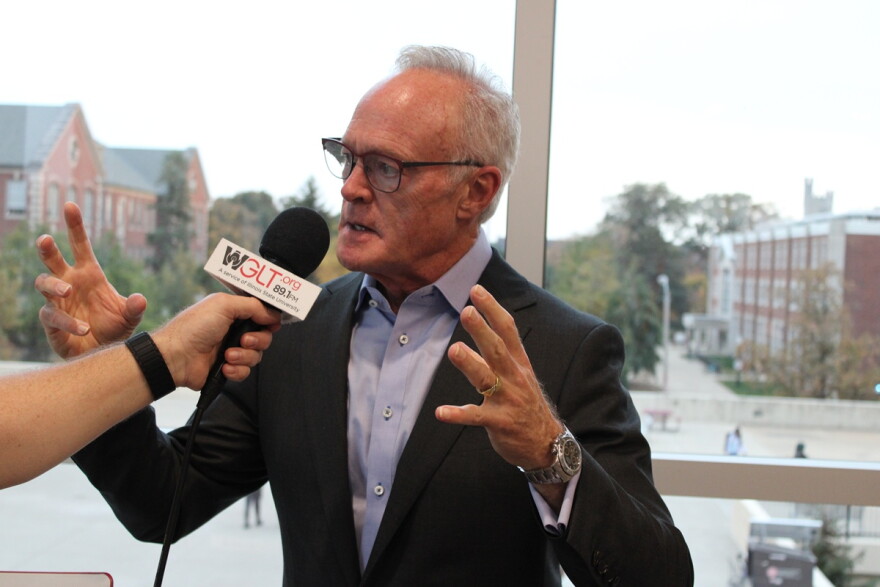 A man talks and gestures in front of a microphone 