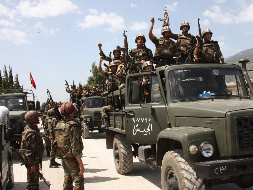 <p>In this photo taken during a government-organized visit for media, Syrian army soldiers shout slogans in support of Assad as they enter a village near the town of Jisr al-Shughour on June 10. Ongoing military operations to crush anti-government protest are draining money from the national budget.</p>