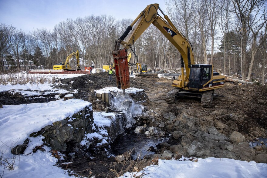 A jackhammer attached to the excavator starts demolishing the stone walls of the Mill Pond Dam on Traphole Brook. (Robin Lubbock/WBUR)