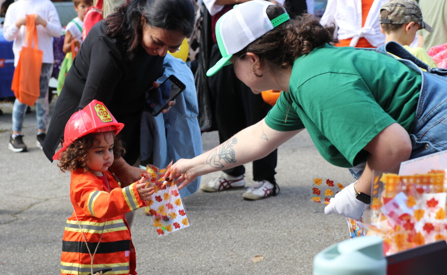 A child receives bags of candy from a community station outside of the Santa Fe College Teaching Zoo on Oct. 28. Dozens of stations lined the exit as families left the zoo. (David Caine/WUFT News)