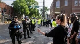A protester confronts a Madison police officer standing in the intersection where Corey Ruiz was shot and killed by an officer as the police and other workers clean the area and re-open it to traffic Tuesday, Aug. 4, 2026, in Madison, Wis.