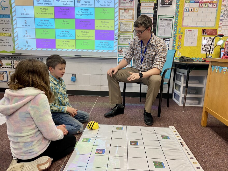 A teacher at Perry Elementary School shows his students how to use a "bee bot" to tell the story of the "Three Little Pigs".