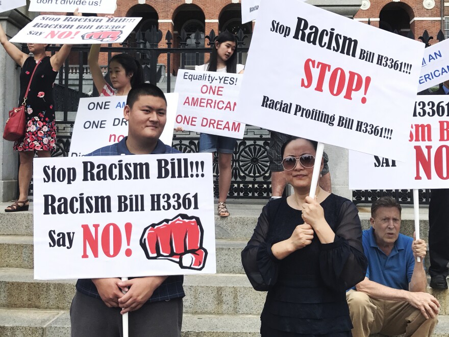 Linglan Zhang (right) of Lexington, Mass., holds a picket sign next to her son, Sean (left), and boyfriend, David Kates (right).